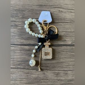 NWT: A parfum bottle with black ribbon and purse charm or keychain.